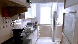 Una cucina con piano di lavoro nero, mobili bianchi, un forno a microonde e un lavello.