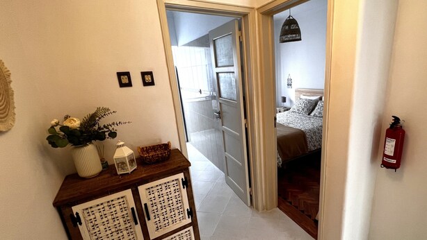 Un corridoio con un armadietto in legno, un estintore e una porta che conduce a una camera da letto.