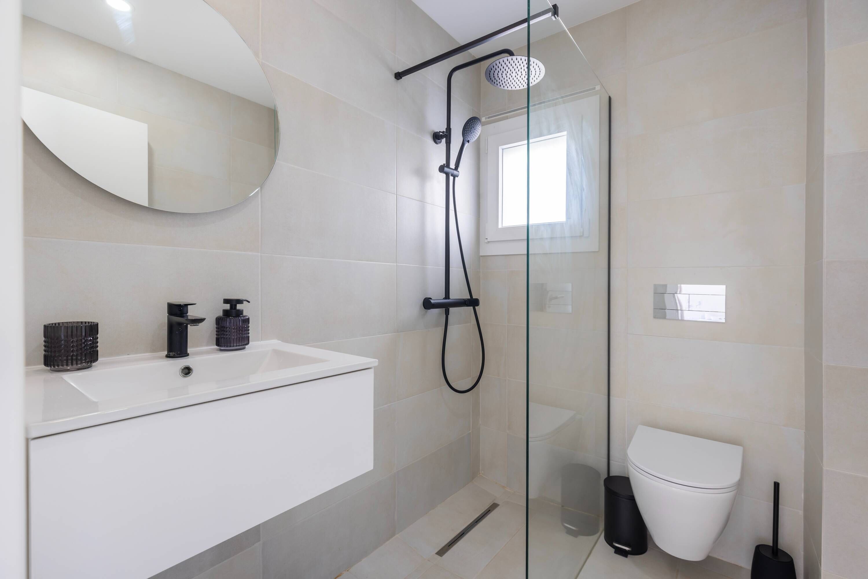 A modern bathroom with a glass-enclosed shower, a white sink, and a toilet.