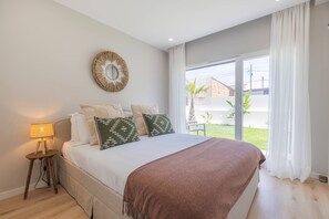 Een slaapkamer met een bed, een bedlamp, decoratie aan de muur en uitzicht op buiten.