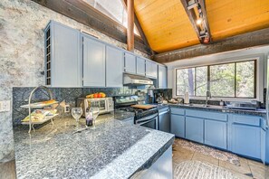 A kitchen with granite countertops, blue cabinets, a built-in oven, and a window providing natural light. - Sedona Wellness Retreat Near Trails & Downtown (Sedona)