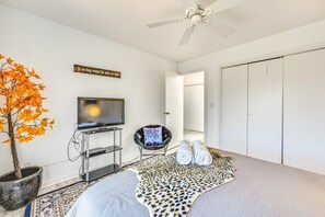 A room with a television on a stand, a chair, a leopard print rug, a potted plant, and a ceiling fan. - Sedona Wellness Retreat Near Trails & Downtown (Sedona)