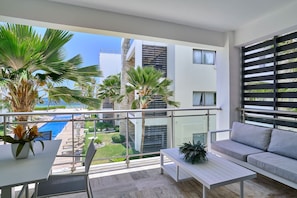 Ein Balkon mit Blick auf einen Pool, einer Couch, einem Tisch und Topfpflanzen.