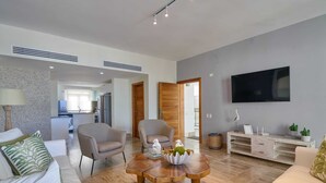 A modern living room with a sofa, armchairs, a coffee table, and a TV.