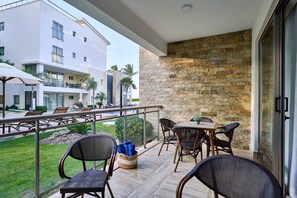 Ein Balkon mit Gartenmöbeln, einer Steinmauer und Blick auf benachbarte Gebäude.