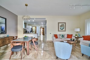 A modern living room with a dining area, a sofa set, and a kitchen in the background. - Apartment - Ground Floor (Punta Cana)