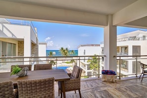 A balcony with a view of the ocean, a dining table with chairs, and a wicker sofa. - Luxury Oceanfront Penthouse in Punta Cana (Punta Cana)
