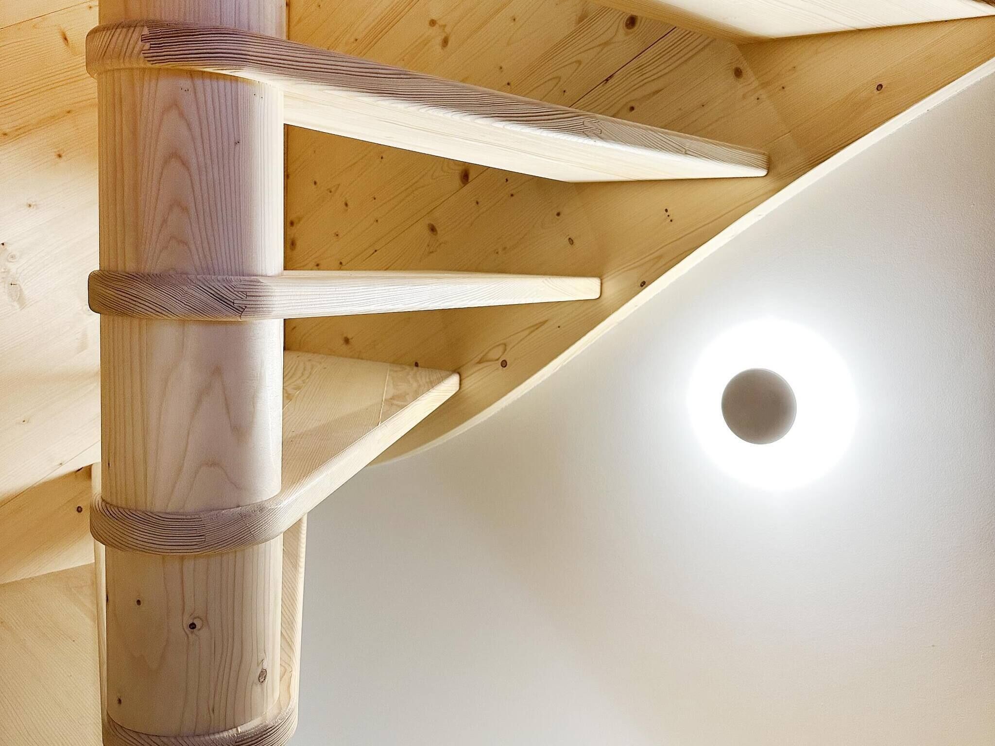 Una escalera de madera con un accesorio de luz circular en la parte superior.