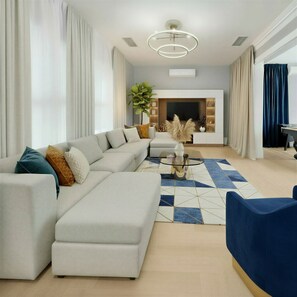 Ein modernes Wohnzimmer mit einem Ecksofa, einem Glastisch und einem blauen Akzentstuhl.