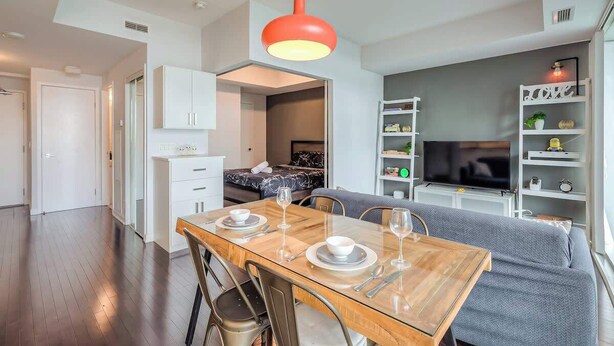 Um espaço de estar moderno com sala de jantar, sofá, televisão e cozinha.