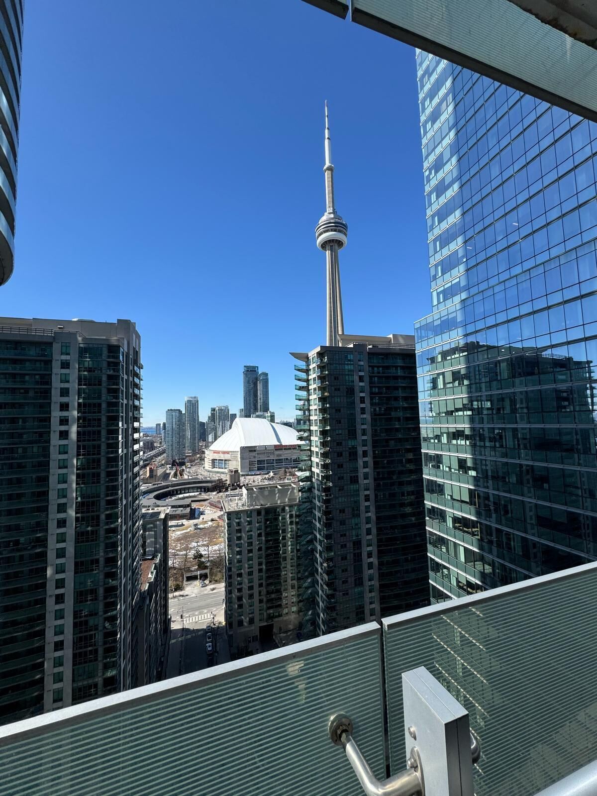 A high-rise building with a view of the CN Tower and a stadium.