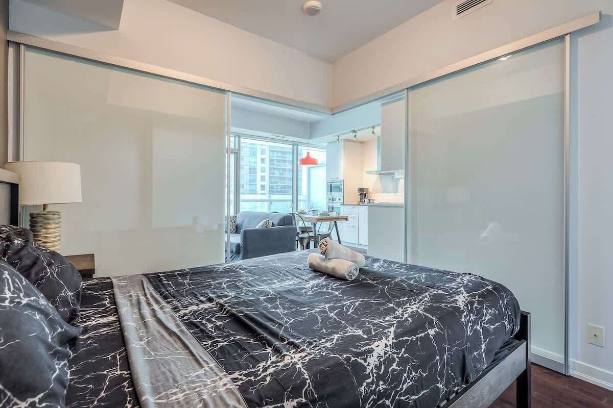 A modern bedroom with a bed, a desk, and a view of the city.