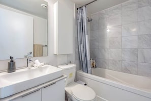 Ein modernes Badezimmer mit Waschbecken, Toilette und Badewanne, alles in Weiß.