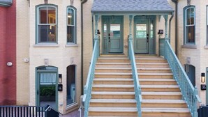 A building with a central staircase, multiple windows, and doors numbered 18, 19, and 20. - 1BR Boutique Lower Suite • Sleeps 4 • Free Parking (Toronto)