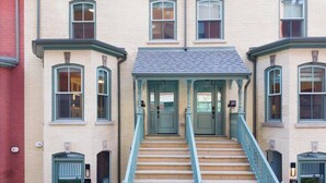 A building with a central staircase, multiple windows, and doors numbered 18, 19, and 20. - 1BR Lower Boutique Suite • Sleeps 4 • WiFi+Parking (Toronto)