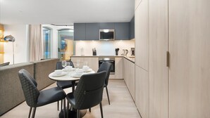 A modern kitchen with a dining area, featuring a built-in oven, microwave, and a large window. - 1BR Lower Boutique Suite • Sleeps 4 • WiFi+Parking (Toronto)