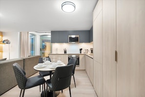 Una cocina moderna con comedor, muebles de madera clara y microondas integrado.