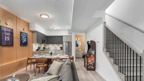 A modern living room with a sofa, dining table, and kitchen area. - Boutique 3BR Townhouse • Free Parking • Sleeps 7 (Toronto)
