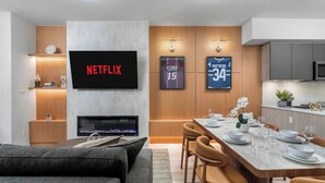 A modern living room with a flat-screen TV, a fireplace, a dining area with a marble table, and a kitchen area. - Boutique 3BR Townhouse • Free Parking • Sleeps 7 (Toronto)