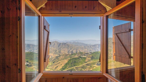 Een kamer met een groot raam dat uitzicht geeft op een bergachtig landschap.