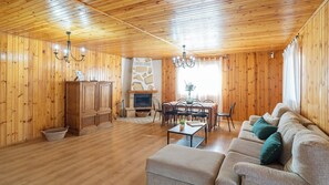 A wooden-paneled room with a fireplace, a dining table with chairs, a sofa, and a chandelier. - Villa Imperator Moclinejo by Ruralidays (Málaga)
