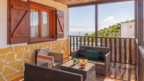 A balcony with wicker furniture, a table with fruit and drinks, and a view of a vineyard. - Villa Imperator Moclinejo by Ruralidays (Málaga)