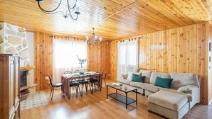 Een gezellig houten interieur met een eethoek, een bank en een open haard.