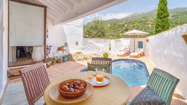 Une terrasse avec une table dressée pour deux personnes, une petite piscine et une vue sur le paysage environnant.