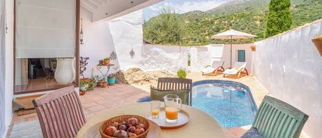 Une terrasse avec une table dressée pour deux personnes, une petite piscine et une vue sur le paysage environnant.