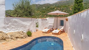 Une piscine avec un sol carrelé, un mur blanc et une vue sur les montagnes en arrière-plan.
