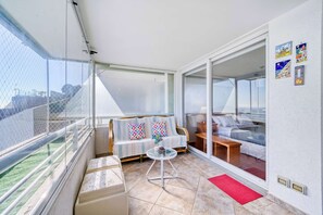 Ein Balkon mit einer Couch, einem kleinen Tisch und einem roten Teppich.