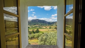 Een uitzicht door een deuropening op een landschap met bergen, velden en bomen.