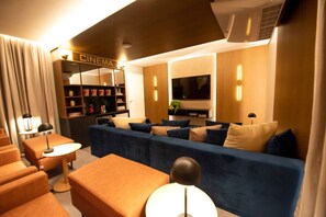 A modern living room with a sofa, ottoman, and a television. - Studio Completo - Vila Olímpia (São Paulo)