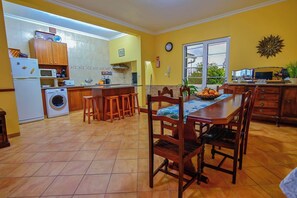 A kitchen with a dining area, a washing machine, and a microwave. - Apartment 3 at Casa da Avo Ines (São Brás)
