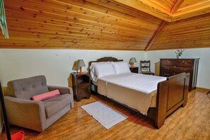 A bedroom with a wooden ceiling, a bed, a chair, a dresser, and a nightstand with lamps. - Apartment 3 at Casa da Avo Ines (São Brás)
