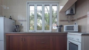 Una cocina con ventana, microondas, estufa y armarios.