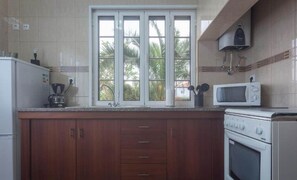 A kitchen with a window, a microwave, a stove, and cabinets. - Apartment 2 at Casa da Avo Ines (São Brás)