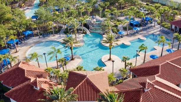 Een resort met meerdere zwembaden, palmbomen en ligbedden.