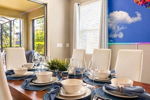 A dining table set for six with white chairs, blue placemats, and clear glassware. - Near Disney & Epic 5BR w/ Pool & Game Room (Davenport)