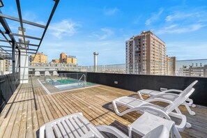Eine Dachterrasse mit Pool, Liegestühlen und Blick auf die umliegenden Gebäude.