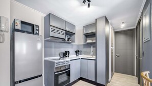 Cozinha compacta com forno embutido, micro-ondas e bancada pequena.