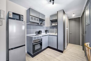 Eine kompakte Küche mit Einbauofen, Mikrowelle und kleiner Arbeitsfläche.