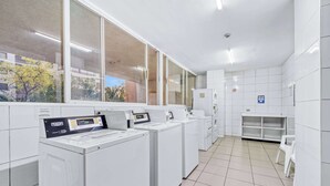 Et vaskeri med flere vaskemaskiner, et lille siddeområde og udsigt gennem store vinduer.