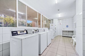 Eine Wäschekammer mit mehreren Waschmaschinen, einer kleinen Sitzecke und Blick durch große Fenster.