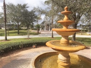 A fountain with multiple tiers in a landscaped area with trees and a building in the background. - Luxury 5 bedroom home with fantastic views pool and lanai. (Davenport)