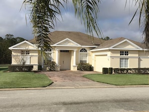 A two-story house with a front entrance, a driveway, and a well-maintained lawn. - Luxury 5 bedroom home with fantastic views pool and lanai. (Davenport)