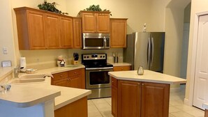 A kitchen with wooden cabinets, a stainless steel refrigerator, a microwave, an oven, and a sink. - Luxury 5 bedroom home with fantastic views pool and lanai. (Davenport)