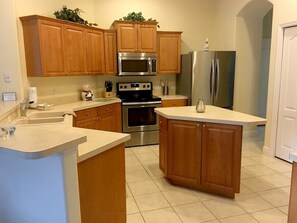 A kitchen with wooden cabinets, a stainless steel refrigerator, a microwave, an oven, and a sink. - Luxury 5 bedroom home with fantastic views pool and lanai. (Davenport)