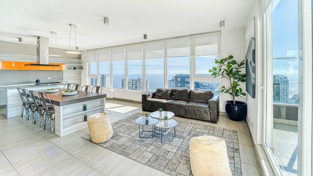 A modern apartment with a kitchen, dining area, living room, and large windows offering city views.