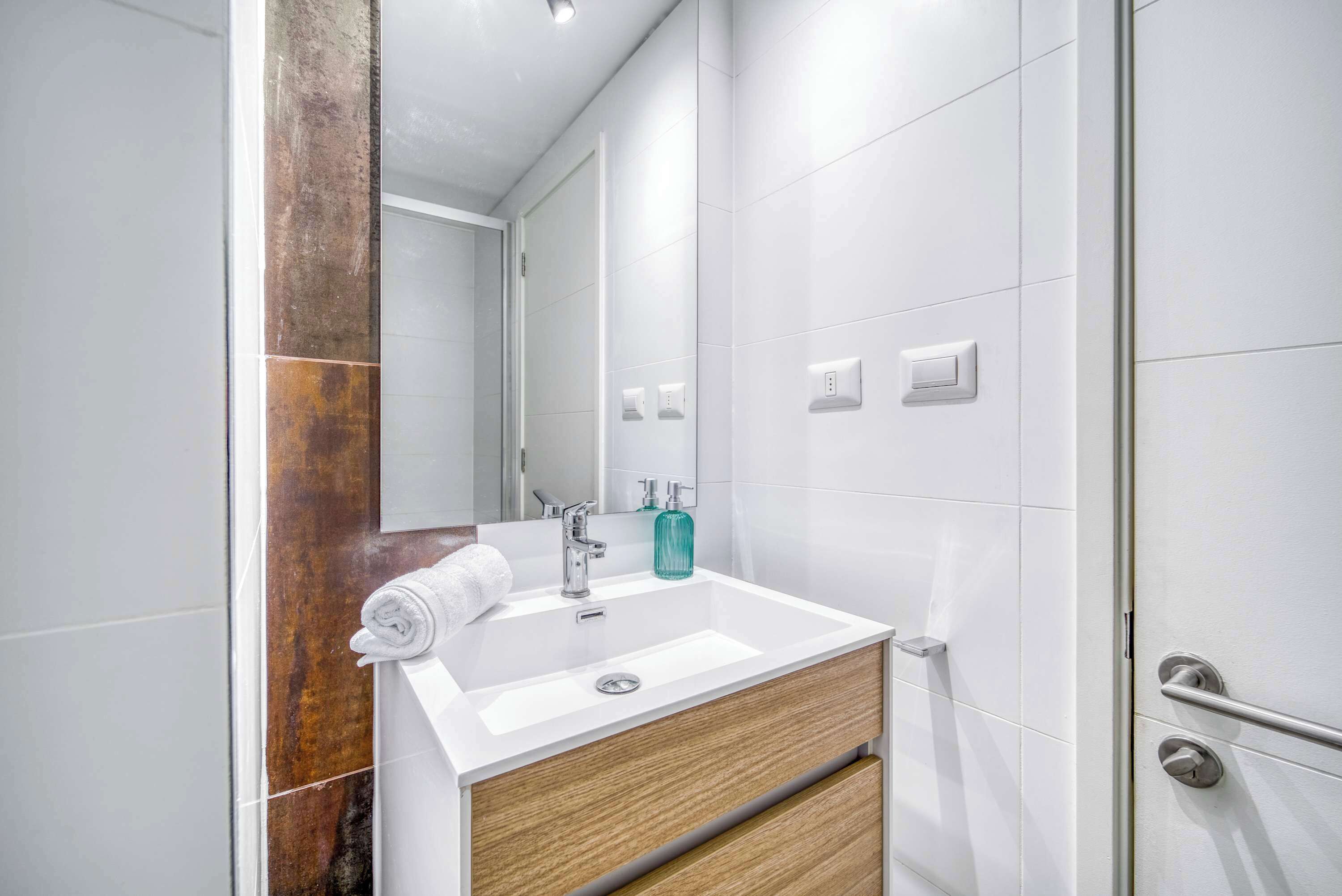 Ein Badezimmer mit Waschbecken, Holzschrank, Spiegel und Handtuch.